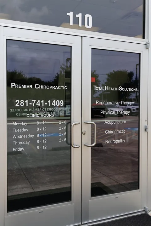 Close-up of the Premier Chiropractic glass entrance doors at Suite 110, showing the clinic name and phone number.