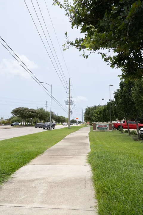 View along Broadway and its sidewalk with the nearby Krispy Kreme roadside sign.