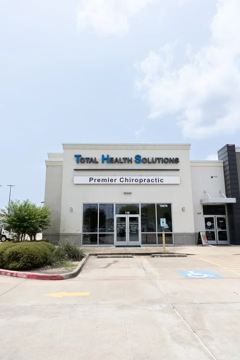 Premier Chiropractic storefront beneath the Total Health Solutions sign, with the Suite 110 entrance and parking spaces.