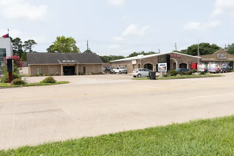Beige Premier Chiropractic clinic and parking area beside neighboring Master Air and flooring storefronts on Broadway.